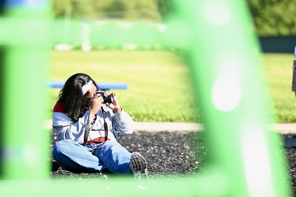 high school student taking photos in a park